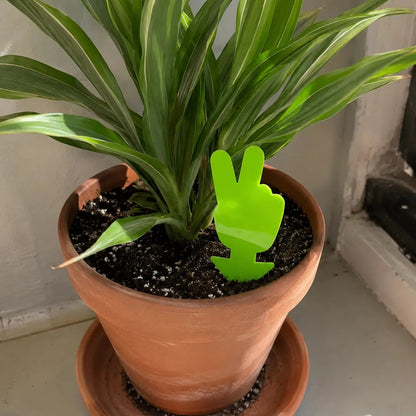 Potted plant with a green peace sign decoration on a neutral background